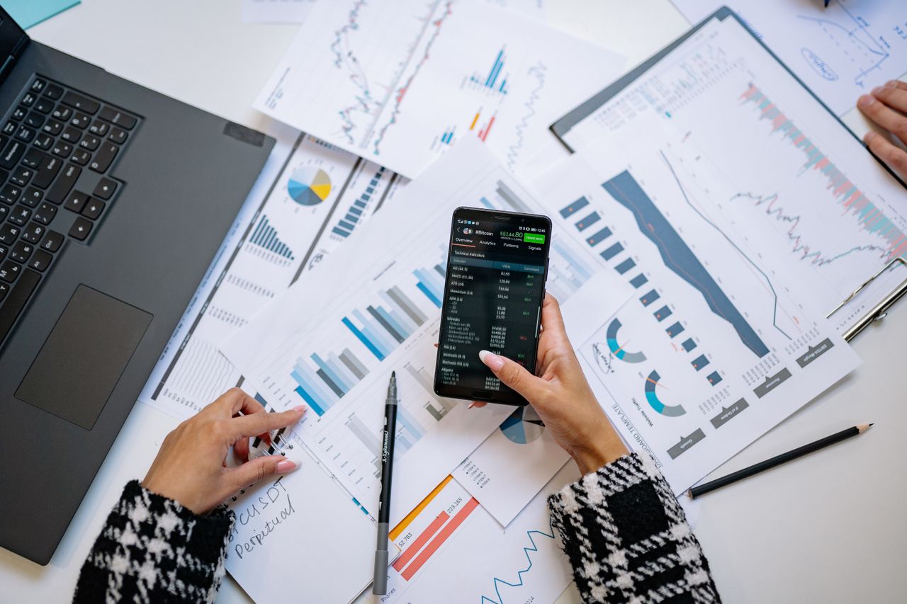 Vue plongeante sur des graphiques et un smartphone dans un bureau, mettant en avant l’analyse de données.